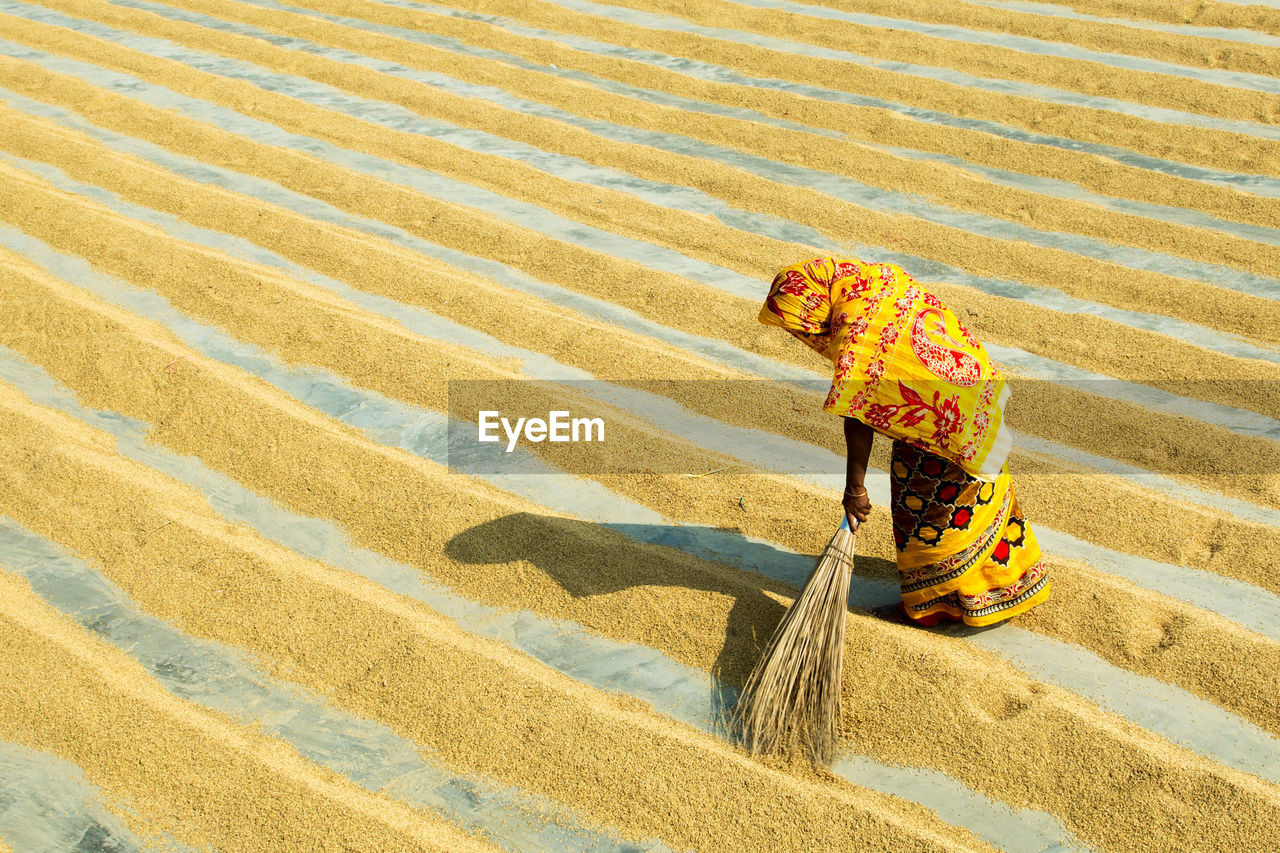 High angle view of woman sweeping grains