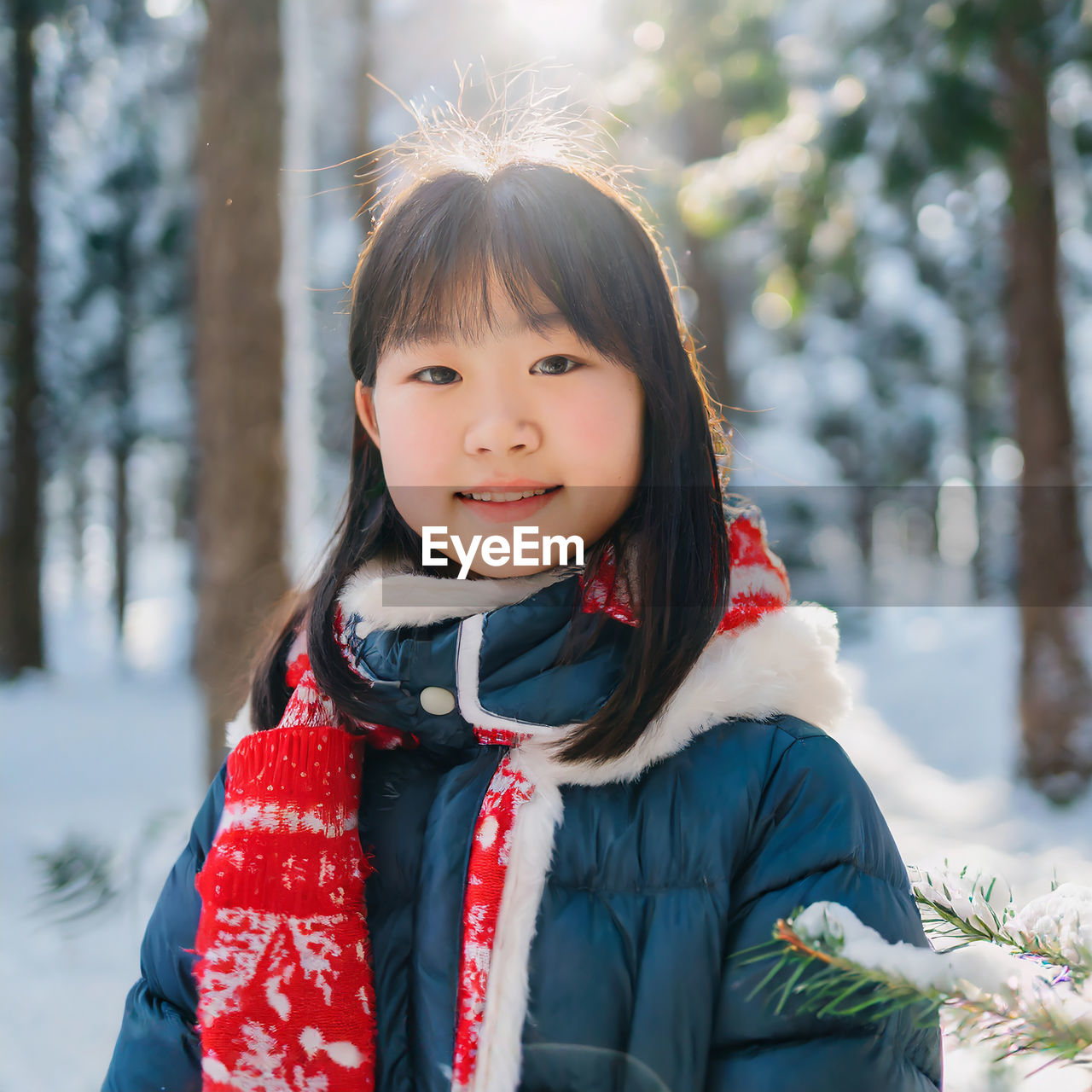 The joy of the winter. portrait of smiling young girl in a snowcapped forest, wearing warm clothes.