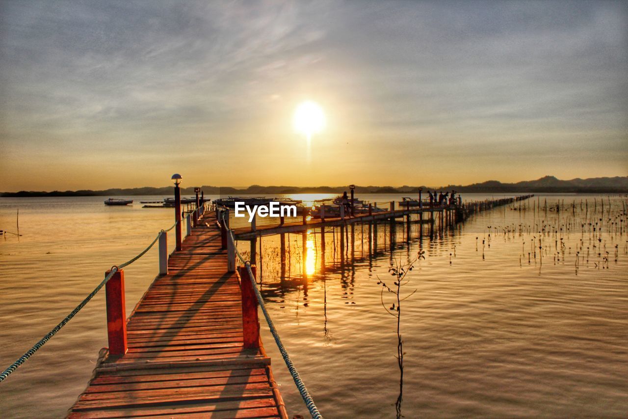 Pier over sea against sky during sunset