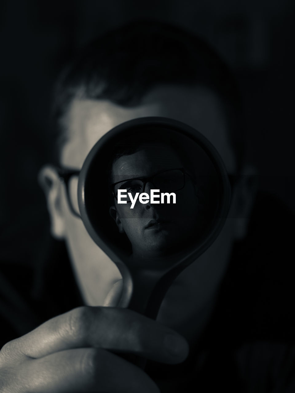 Portrait of man looking through magnifying glass in darkroom