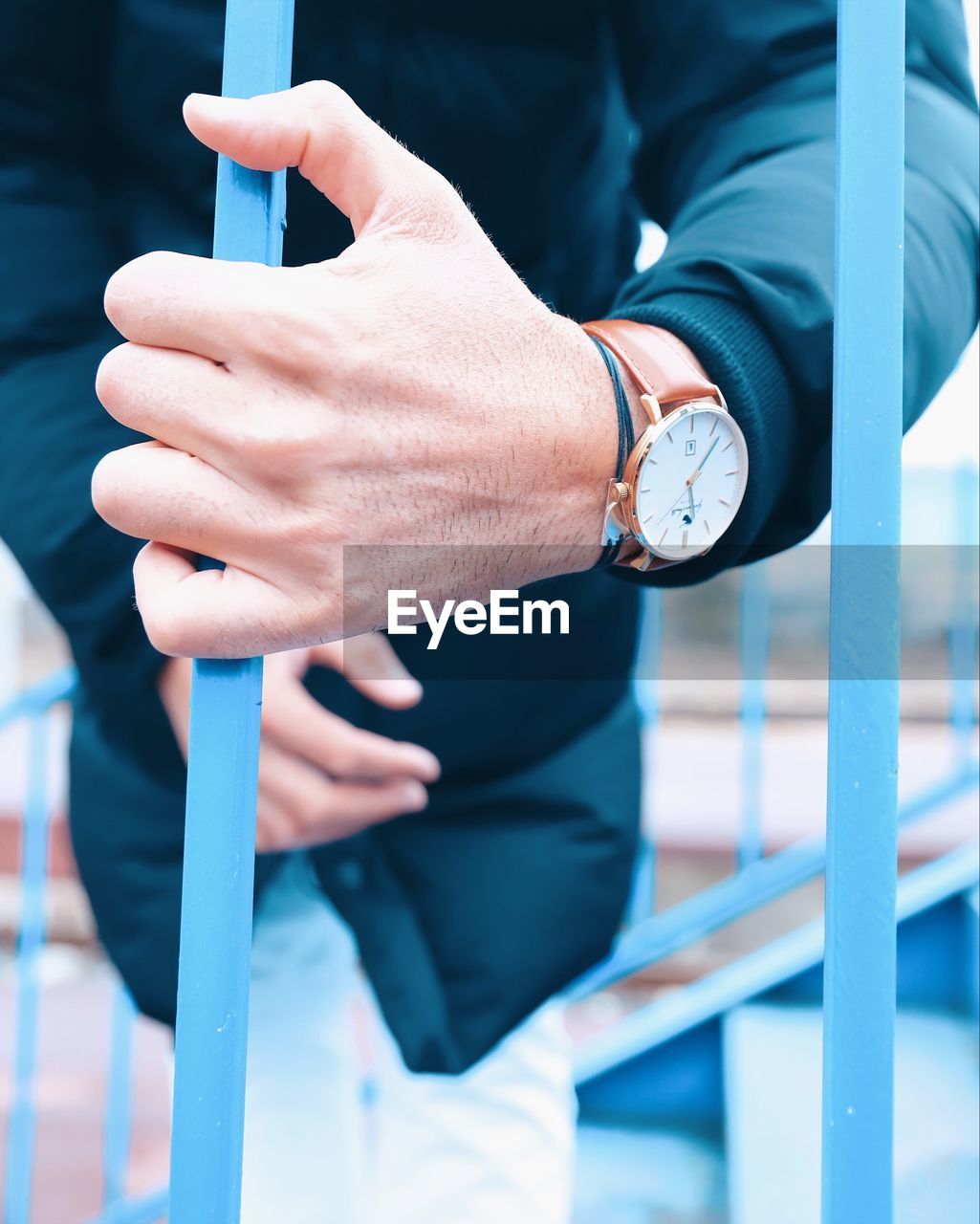 MIDSECTION OF MAN STANDING ON RAILING