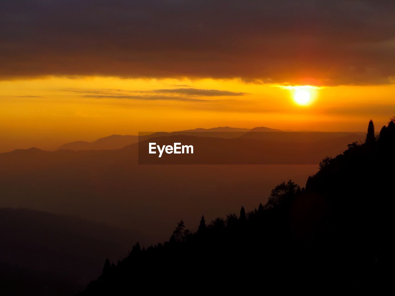 Scenic view of silhouette mountains against orange sky