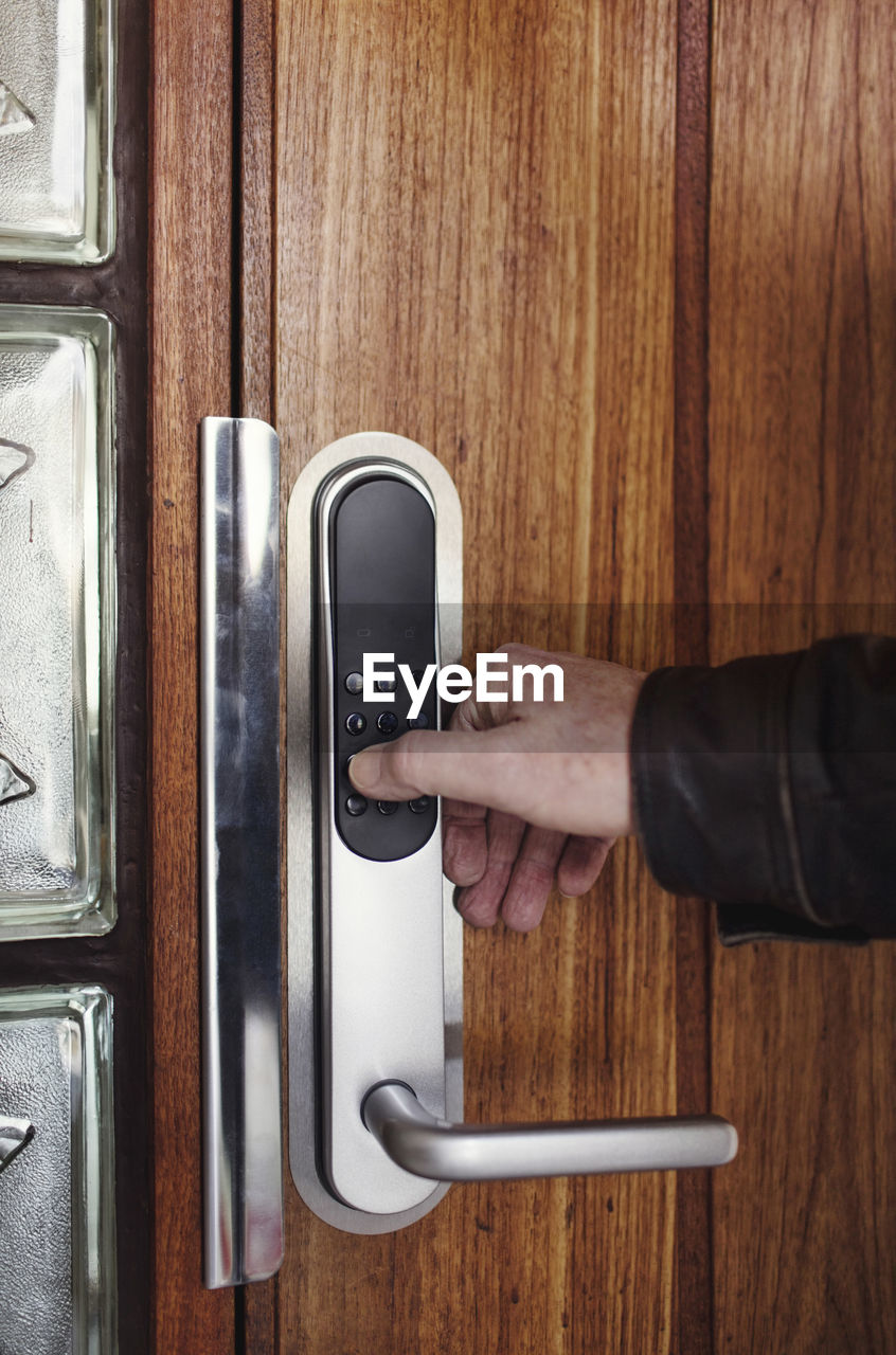 Cropped image of senior man opening electric lock on wooden door