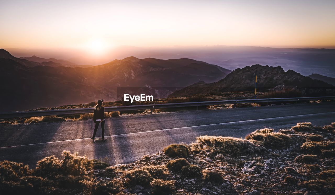 High angle view of woman skateboarding on country road against mountains