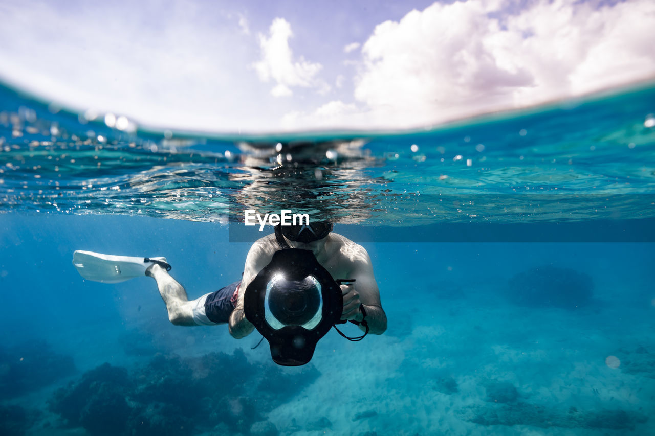 Underwater photographer in split level photo on sunny hawaii day