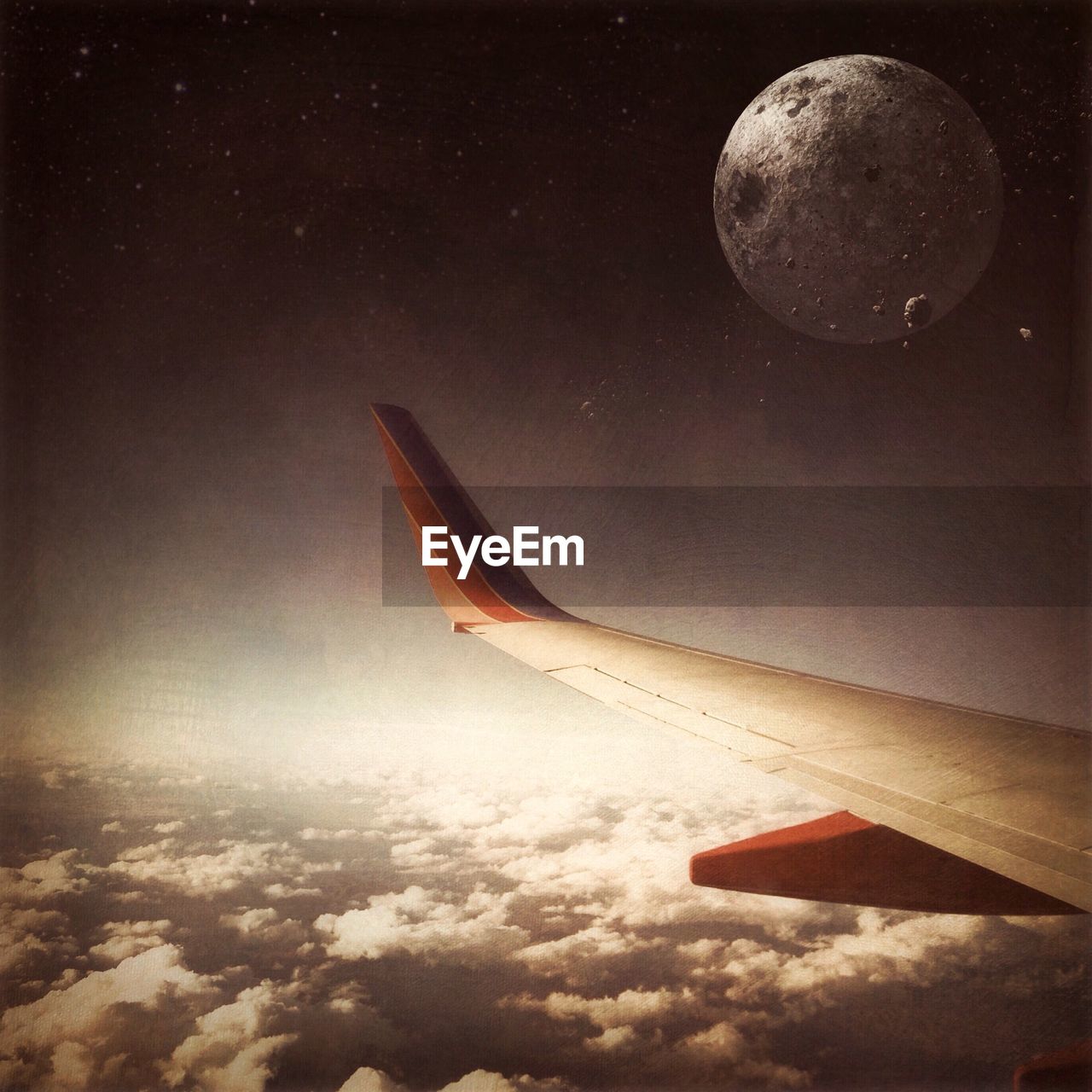 Cropped aircraft wing over clouds against moon