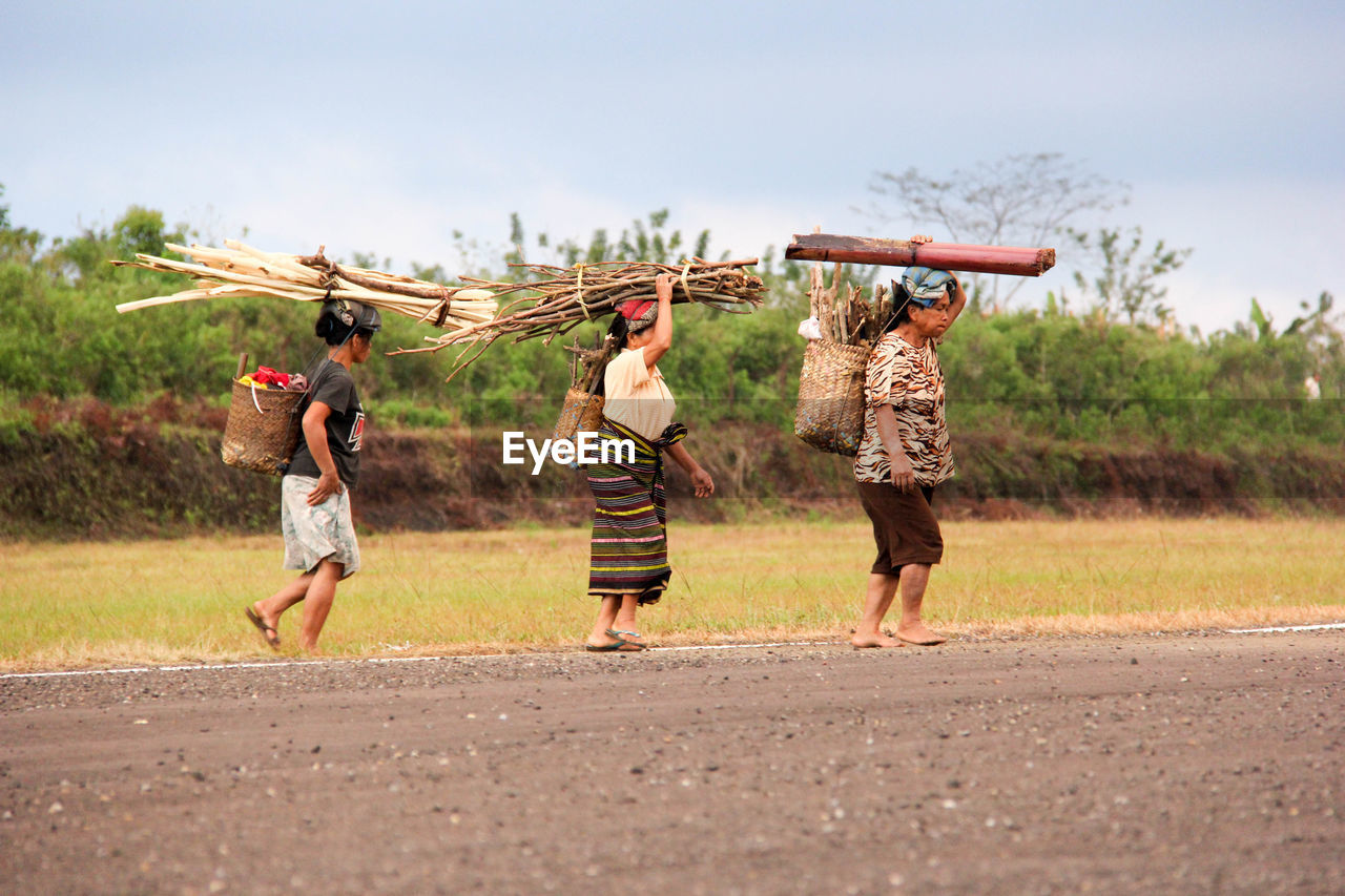 REAR VIEW OF PEOPLE WALKING ON FARM