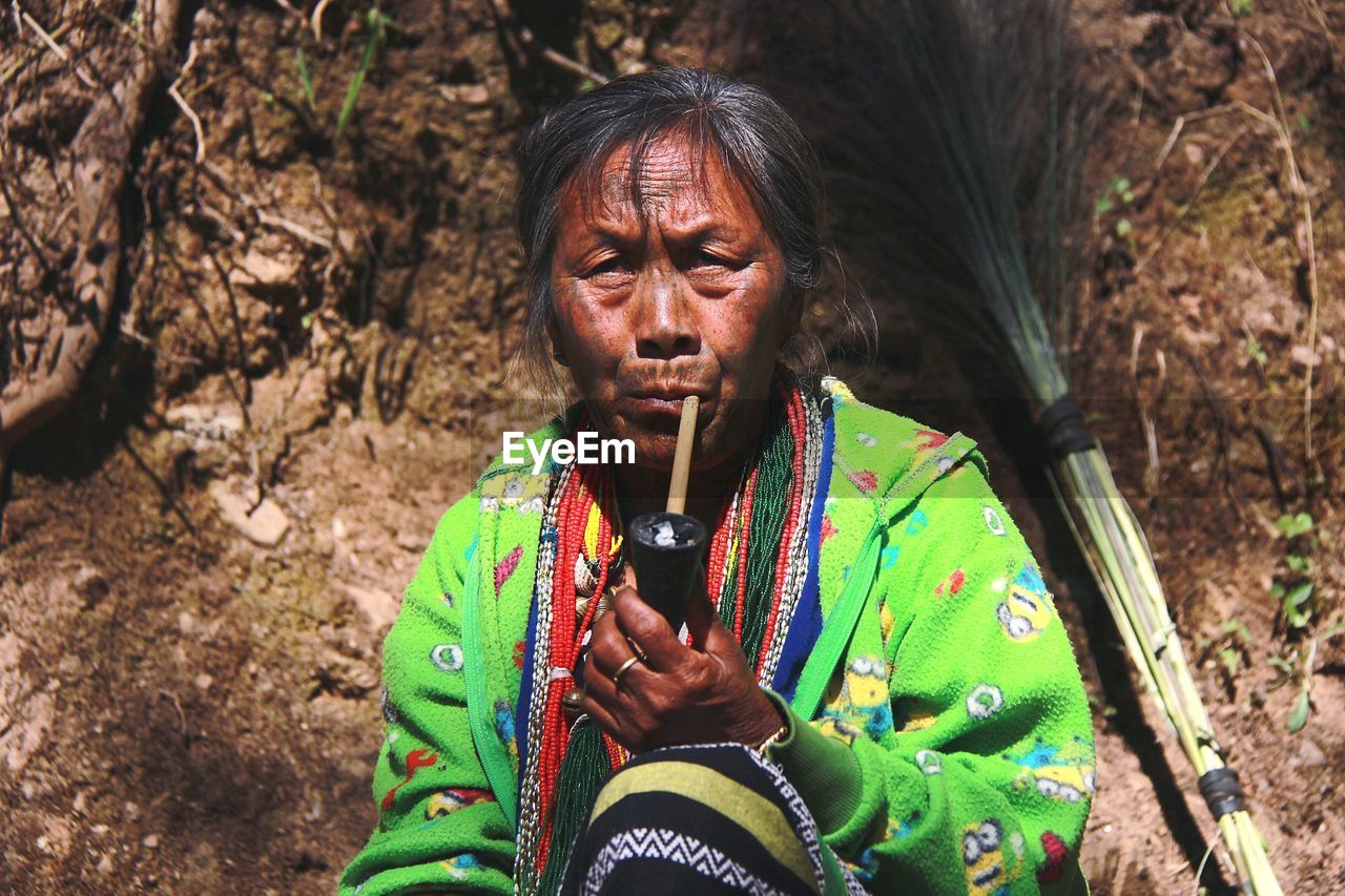 Portrait of woman smoking pipe while sitting outdoors