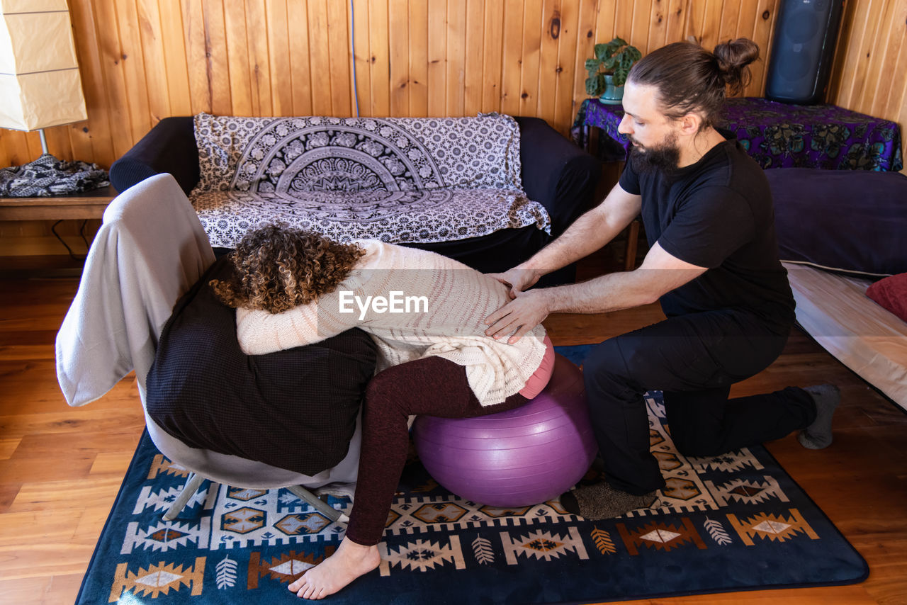 side view of young woman using mobile phone while sitting on sofa at home