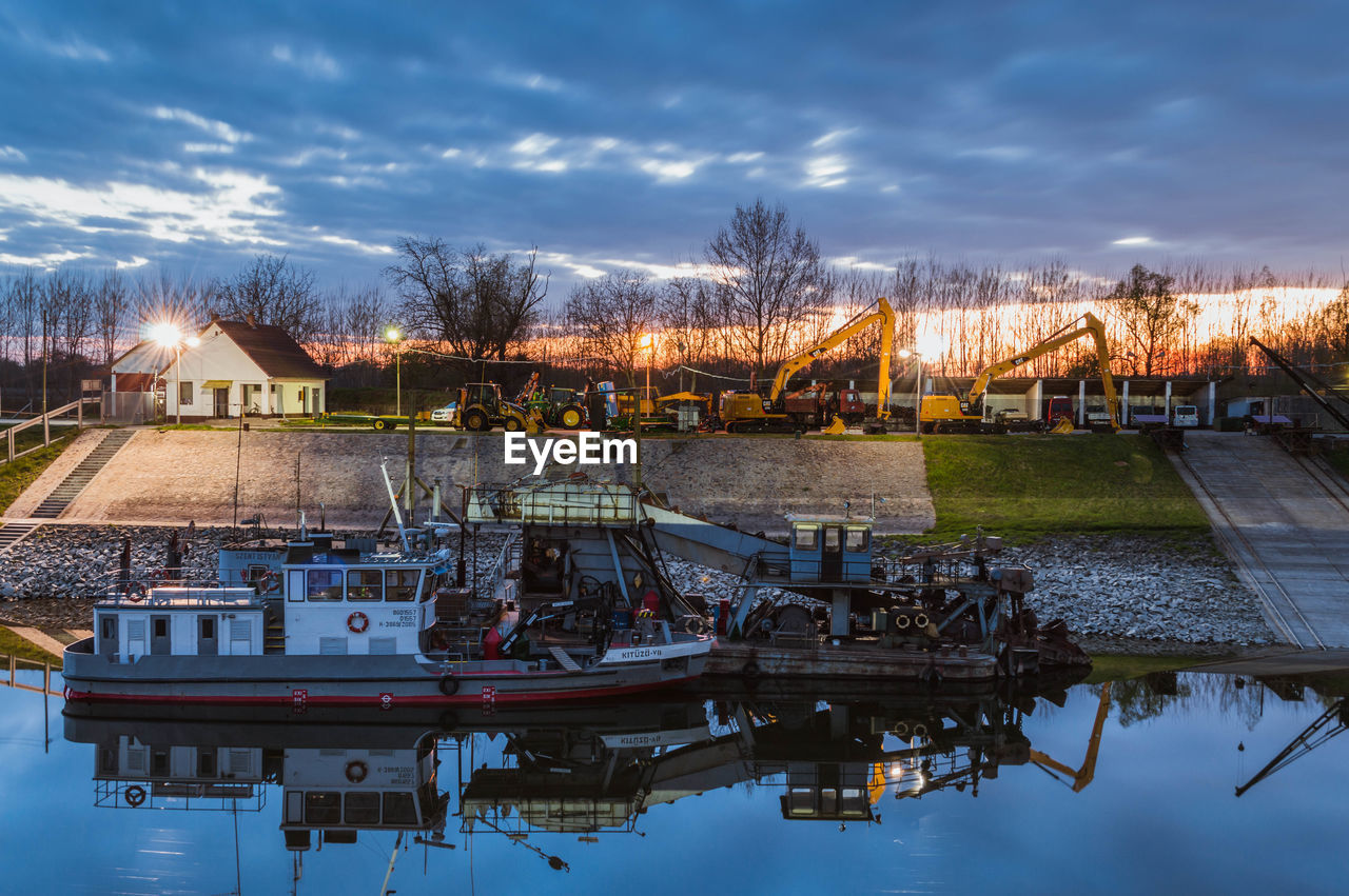 Boats in river against cloudy sky during sunrise