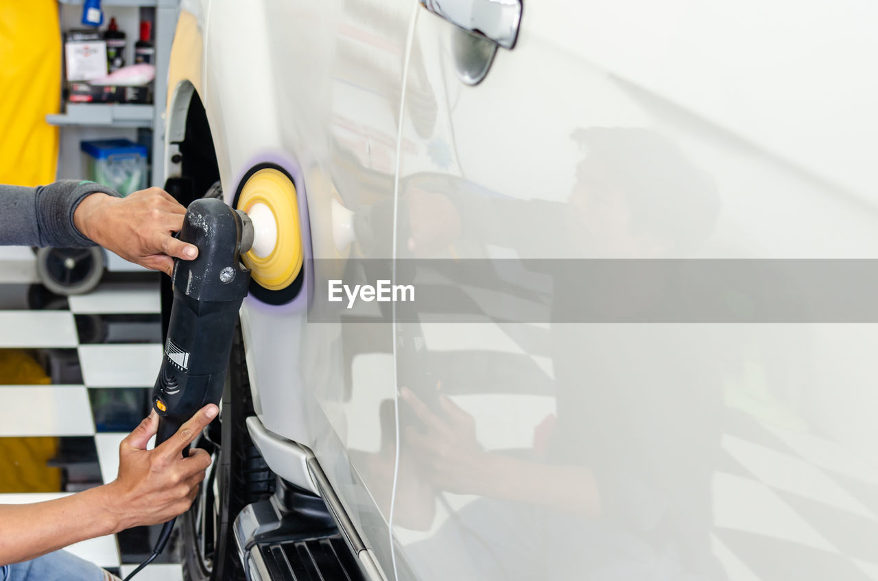 CLOSE-UP OF MAN WORKING ON CAR