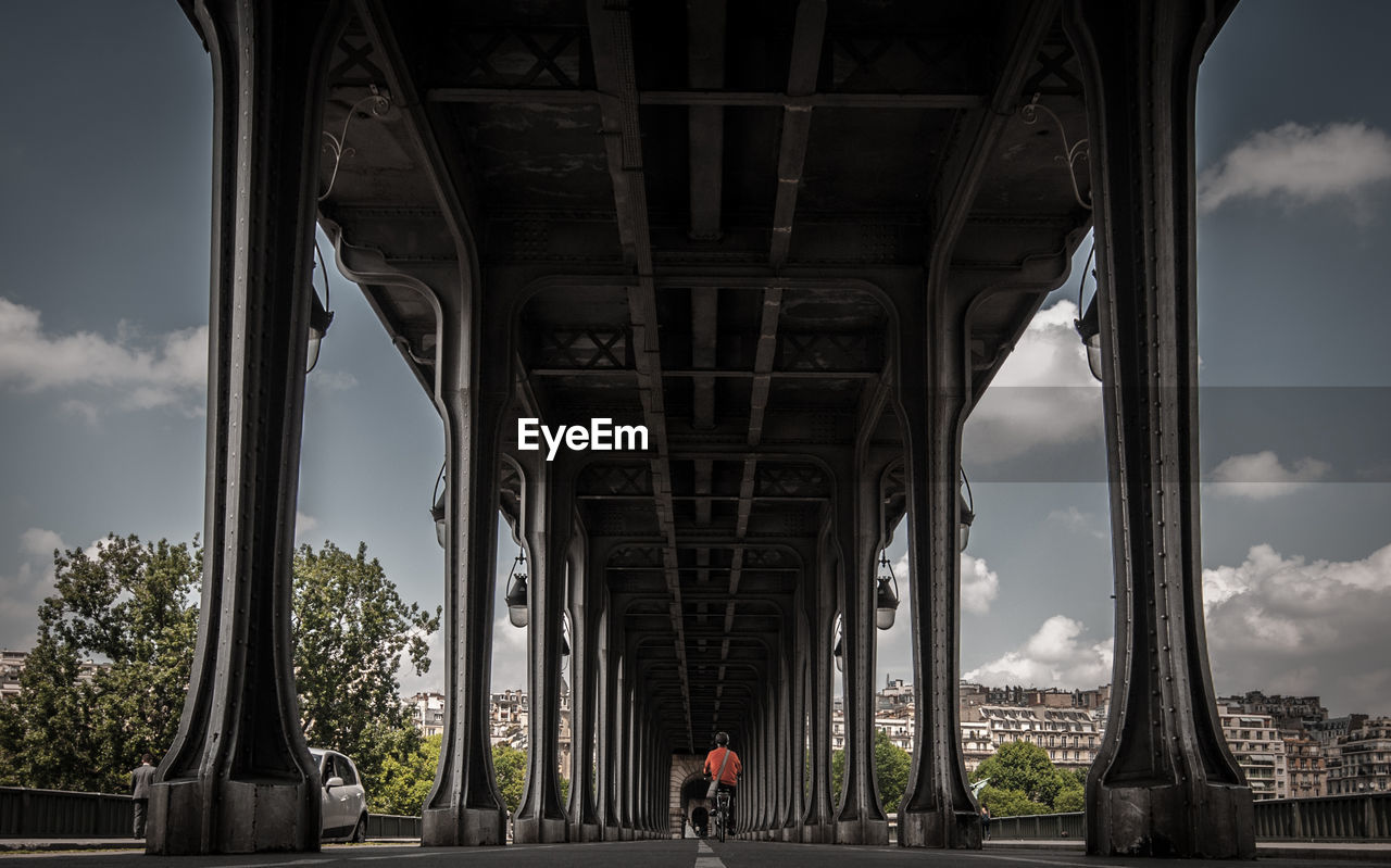 Surface level of man riding bicycle under bridge