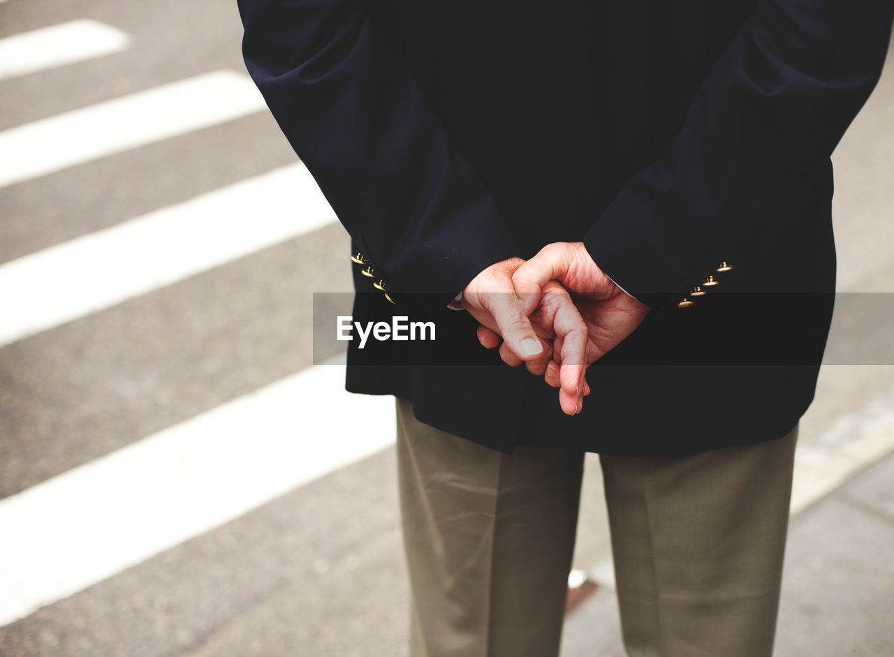 Close-up of man standing with hands behind back