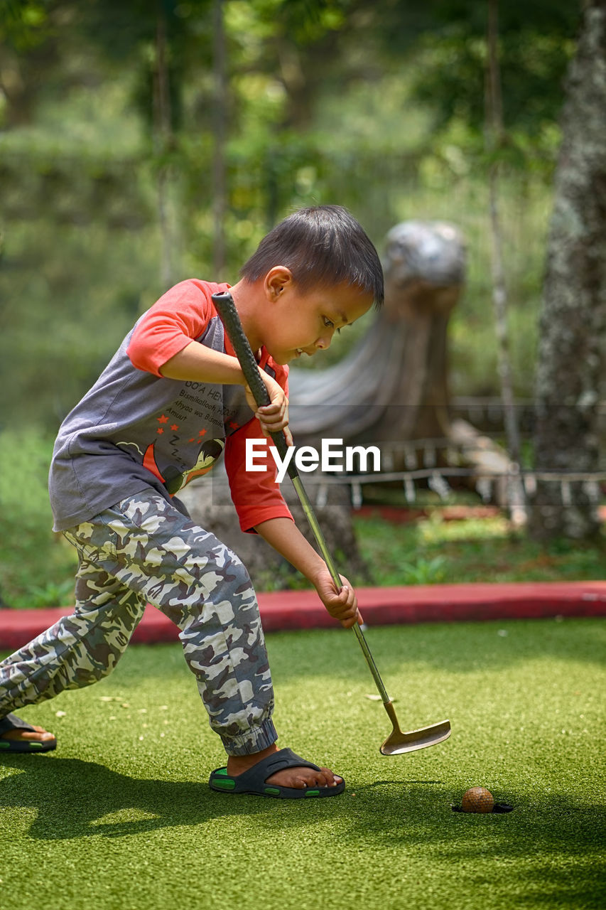 Boy playing golf on grassy field