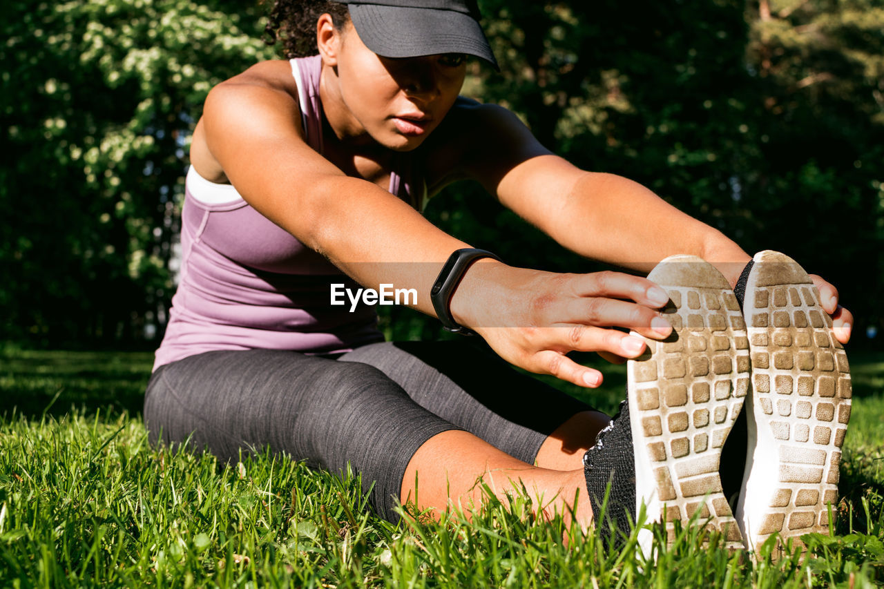 Full length of woman exercising on grassy field at park