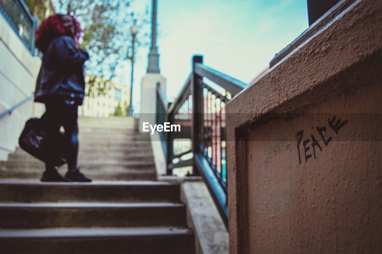 Low angle view of woman standing on staircase with peace text