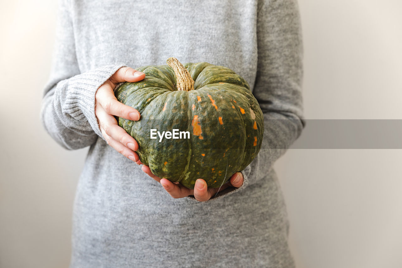 midsection of man with pumpkin