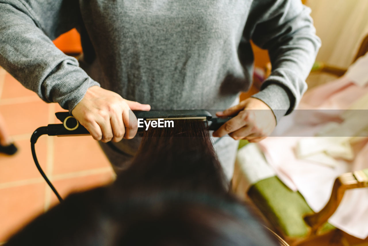 Midsection of beautician working on customer hair in salon