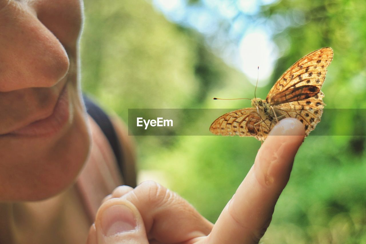 Cropped image of woman holding butterfly on finger