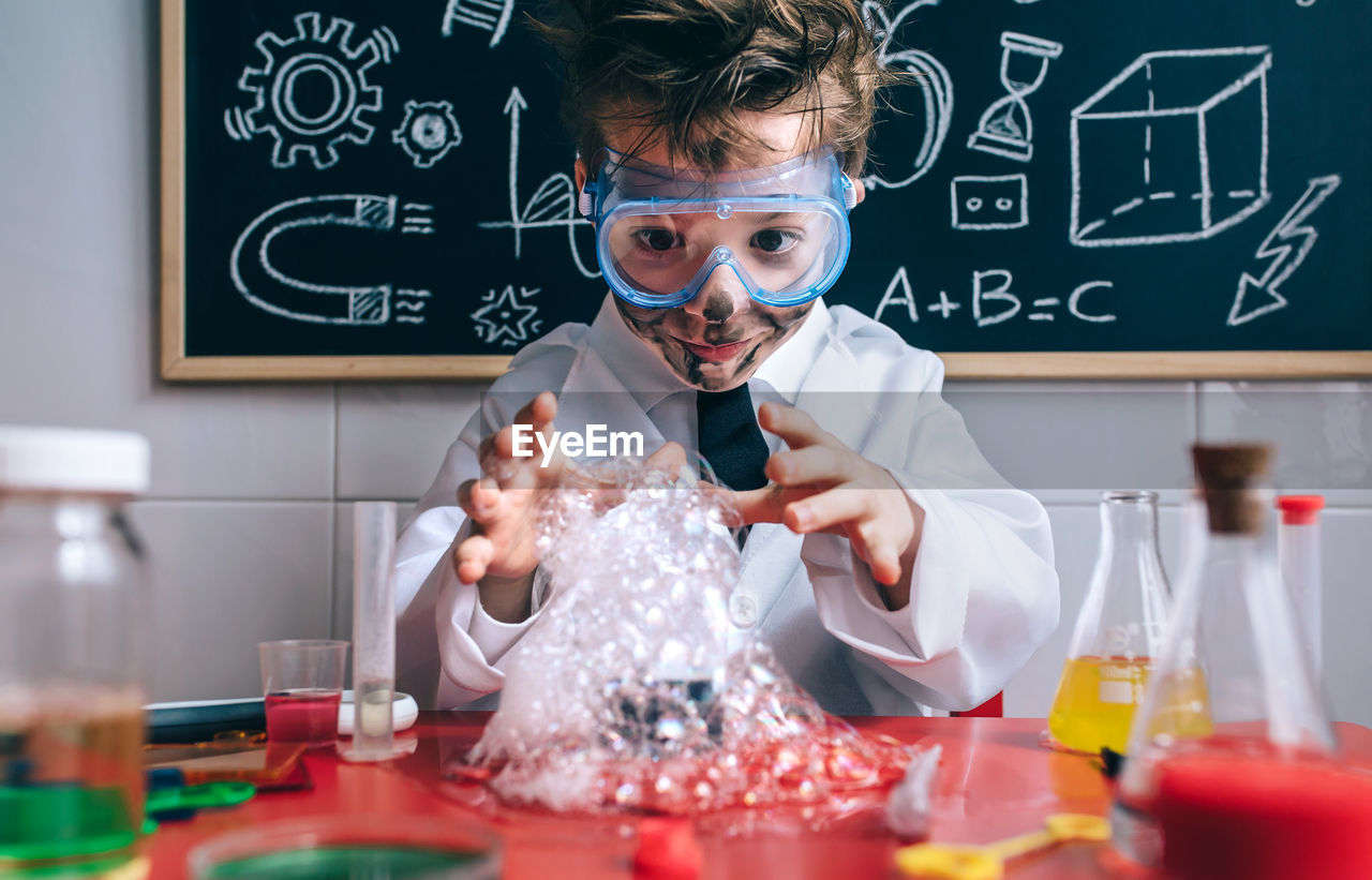 Boy wearing lap coat while standing in classroom