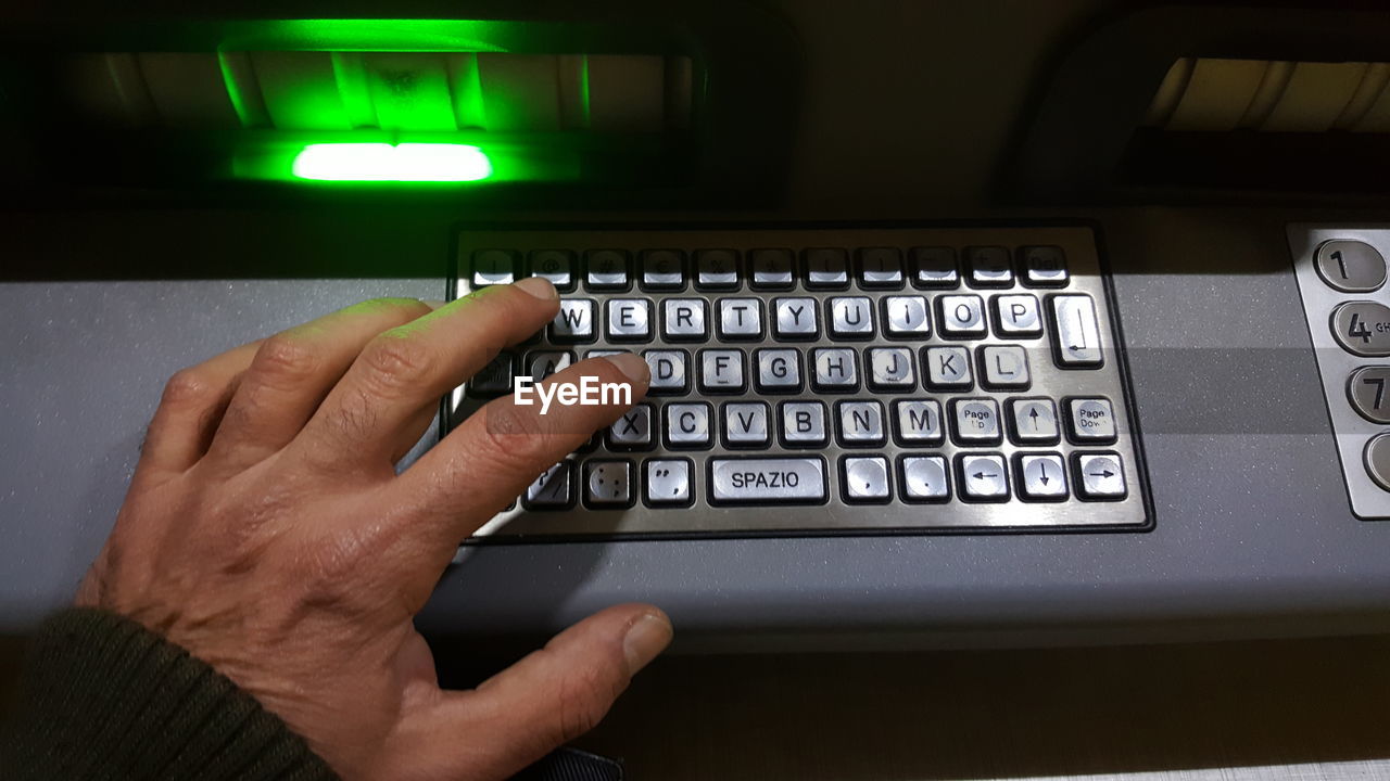 Cropped hand typing password on machine