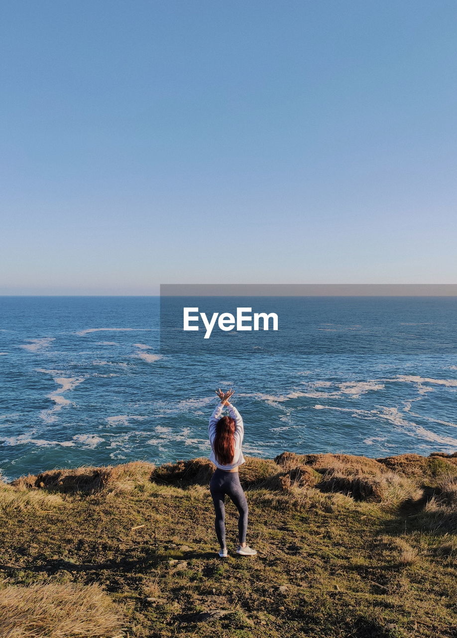 Rear view of woman on beach against clear sky