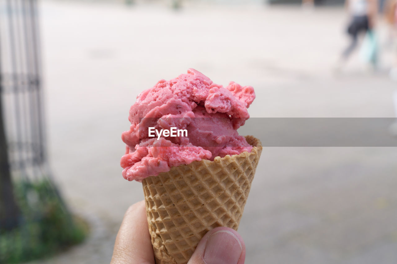 A waffle with a scoop of strawberry ice cream in hand