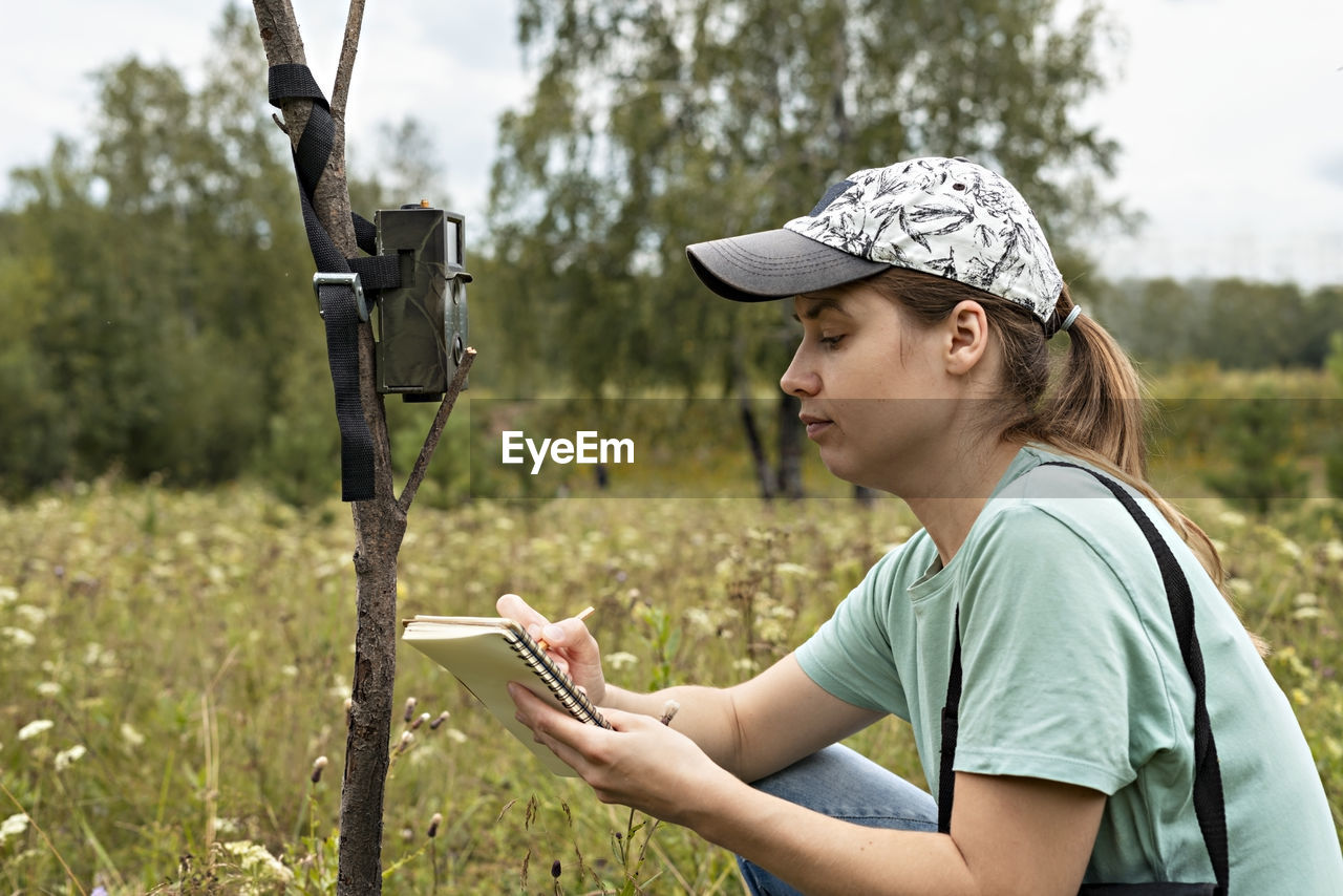 SIDE VIEW OF SENIOR WOMAN USING MOBILE PHONE ON LAND