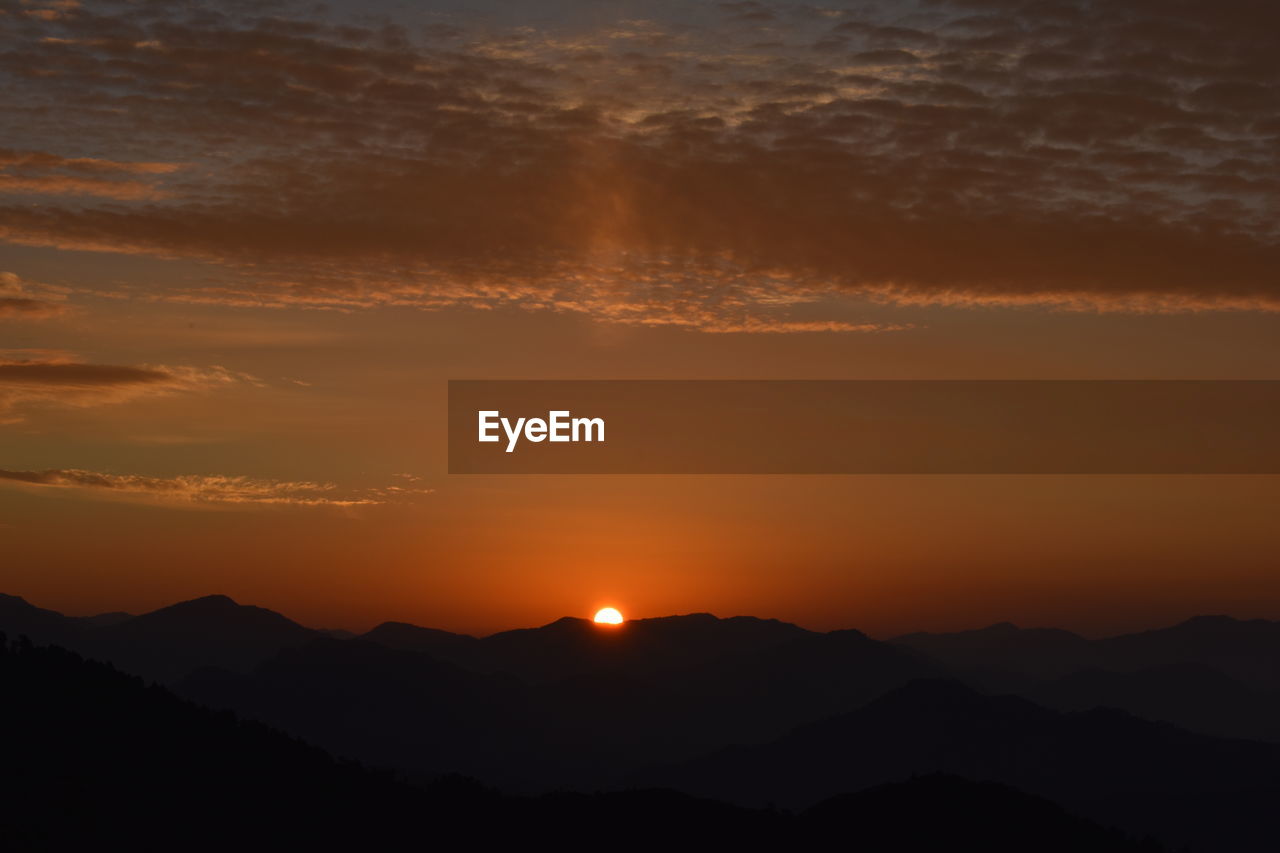 SCENIC VIEW OF SILHOUETTE MOUNTAINS AGAINST ORANGE SKY