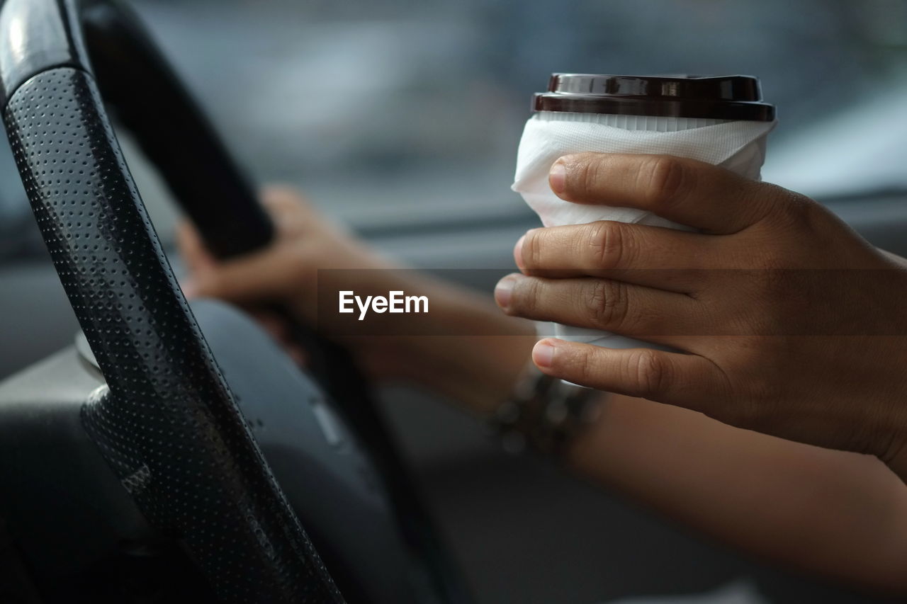 Close-up of hand holding disposable cup while driving car