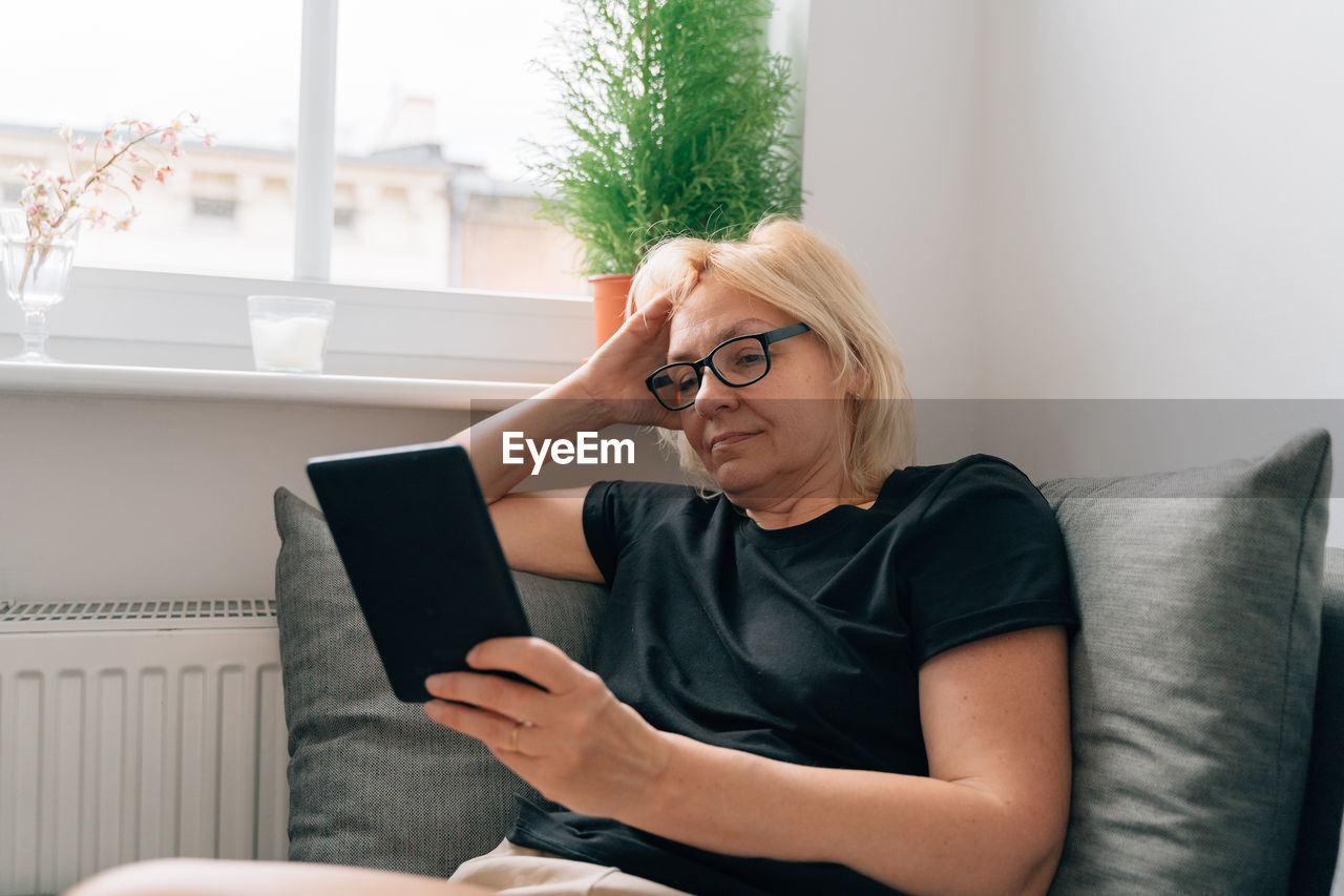 Young woman using laptop while sitting on sofa at home