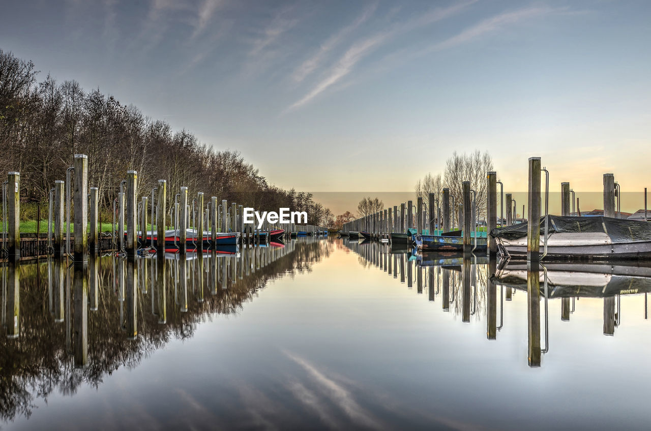 Sailboats moored in river with city in background