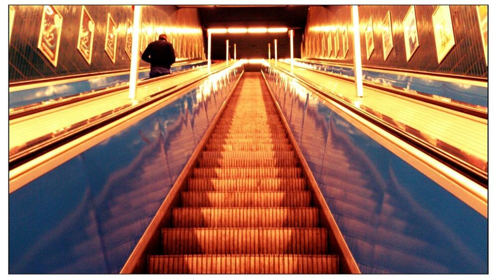 Low angle view of man on illuminated escalator