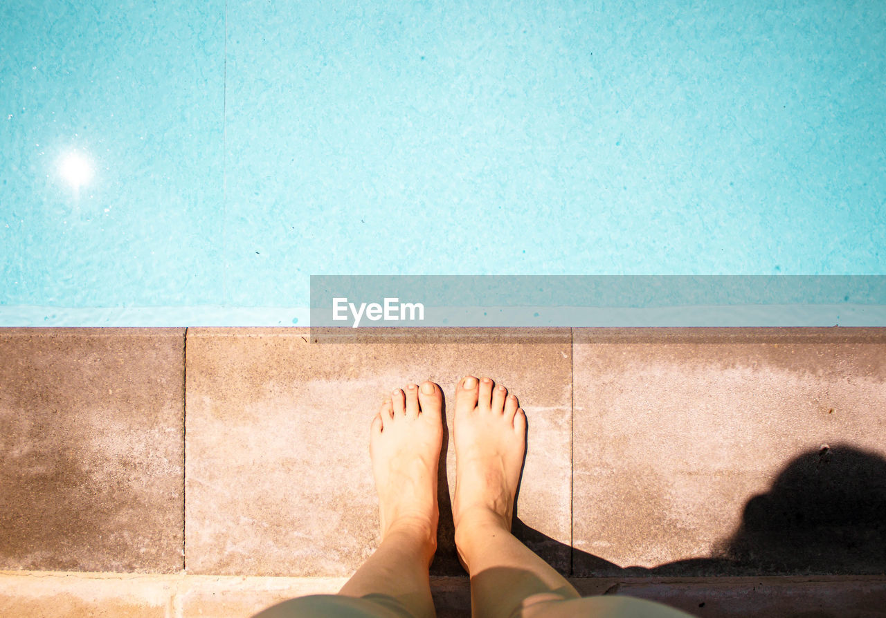 Female legs and feet in blue swimming pool