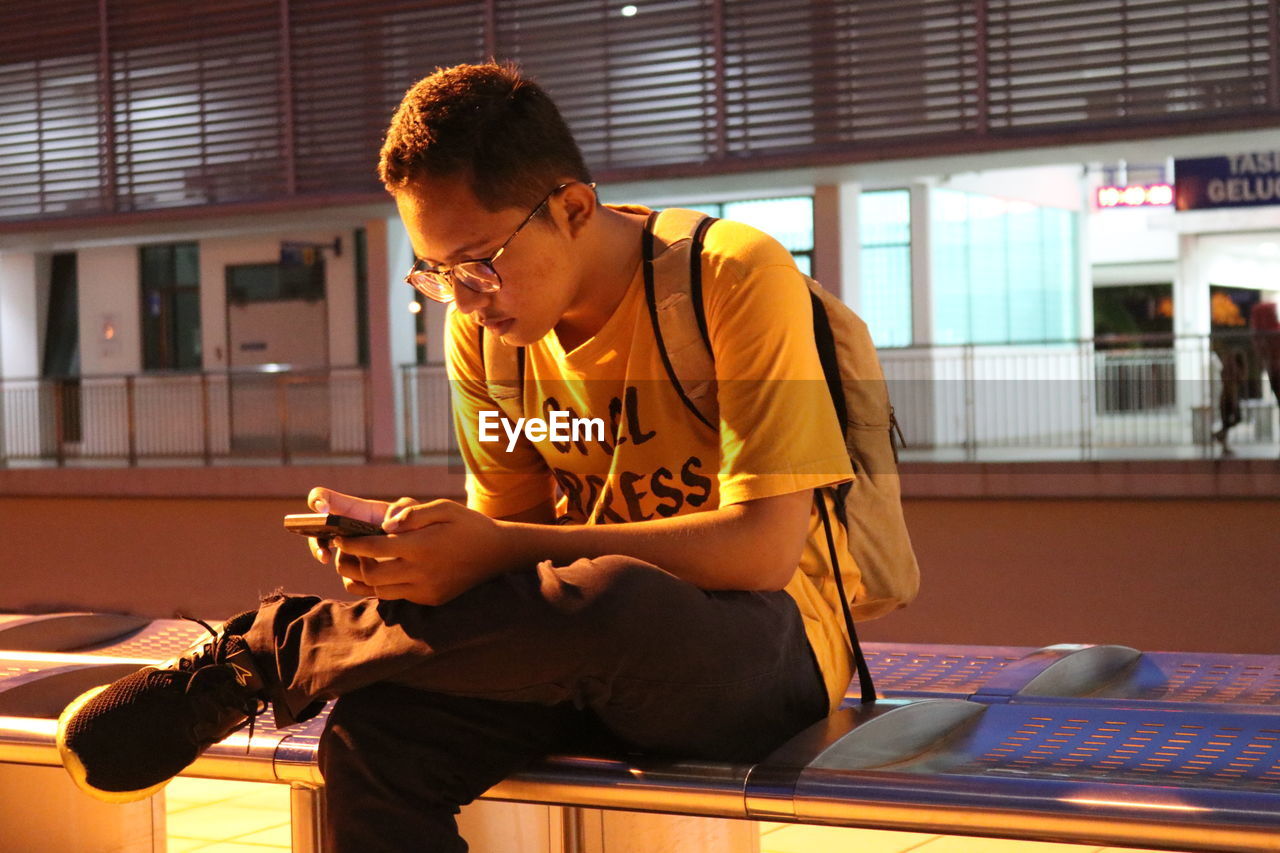 Young man using smart phone while sitting on bench