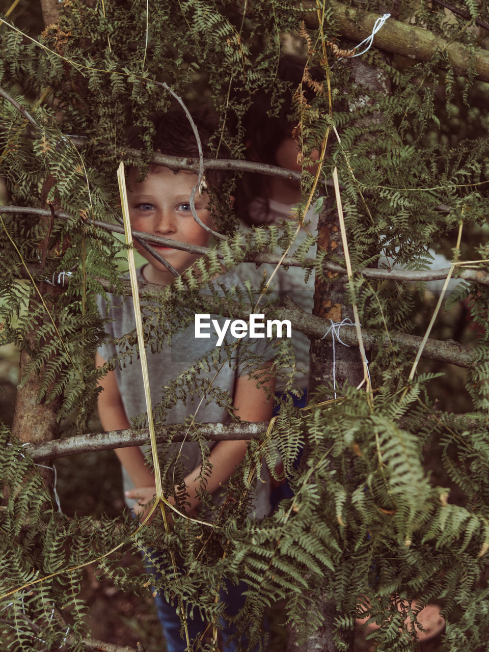 Caucasian child in a hut made of branches and leaves
