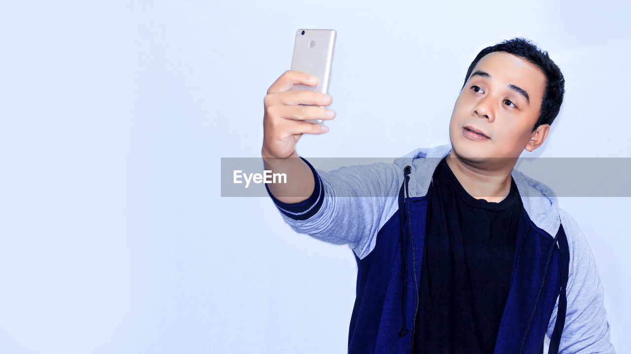 Man taking selfie against white background