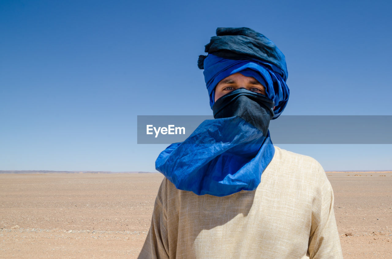 Portrait of man wearing headscarf at desert