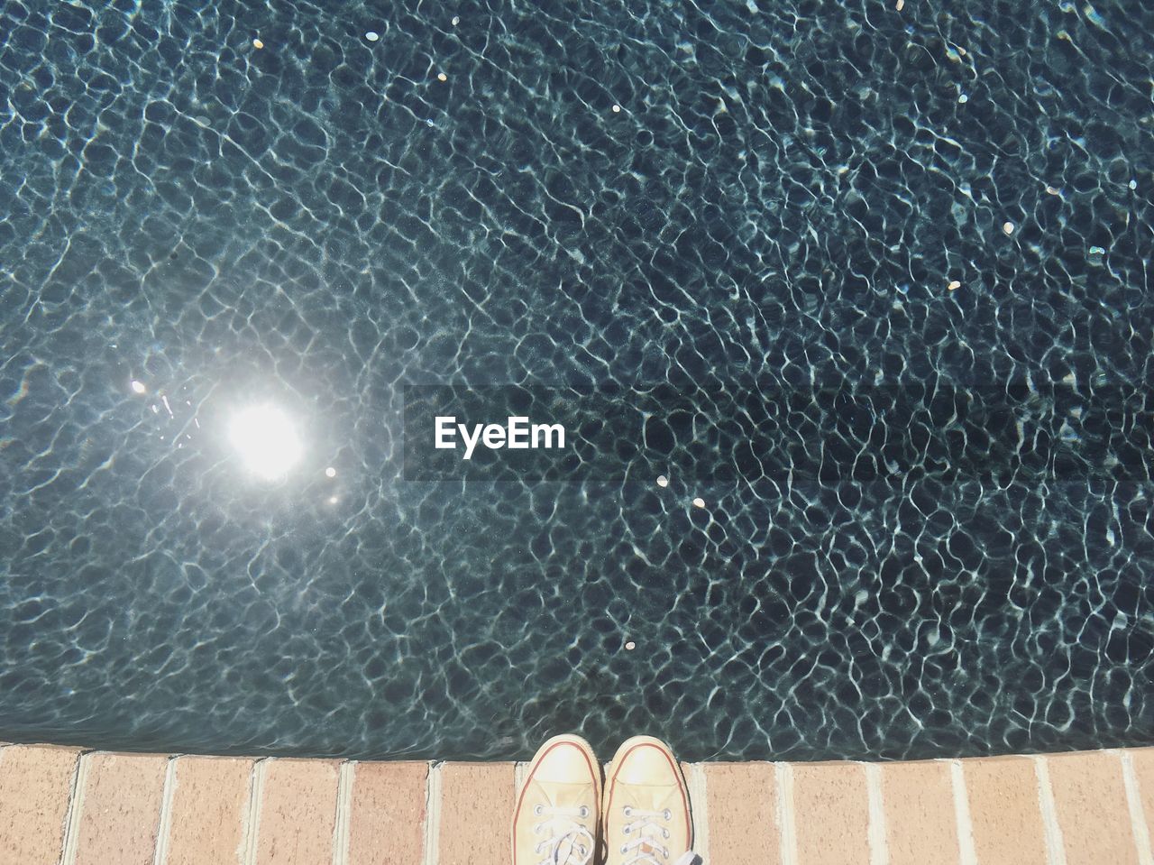 Directly above shot of shoes by swimming pool during sunny day