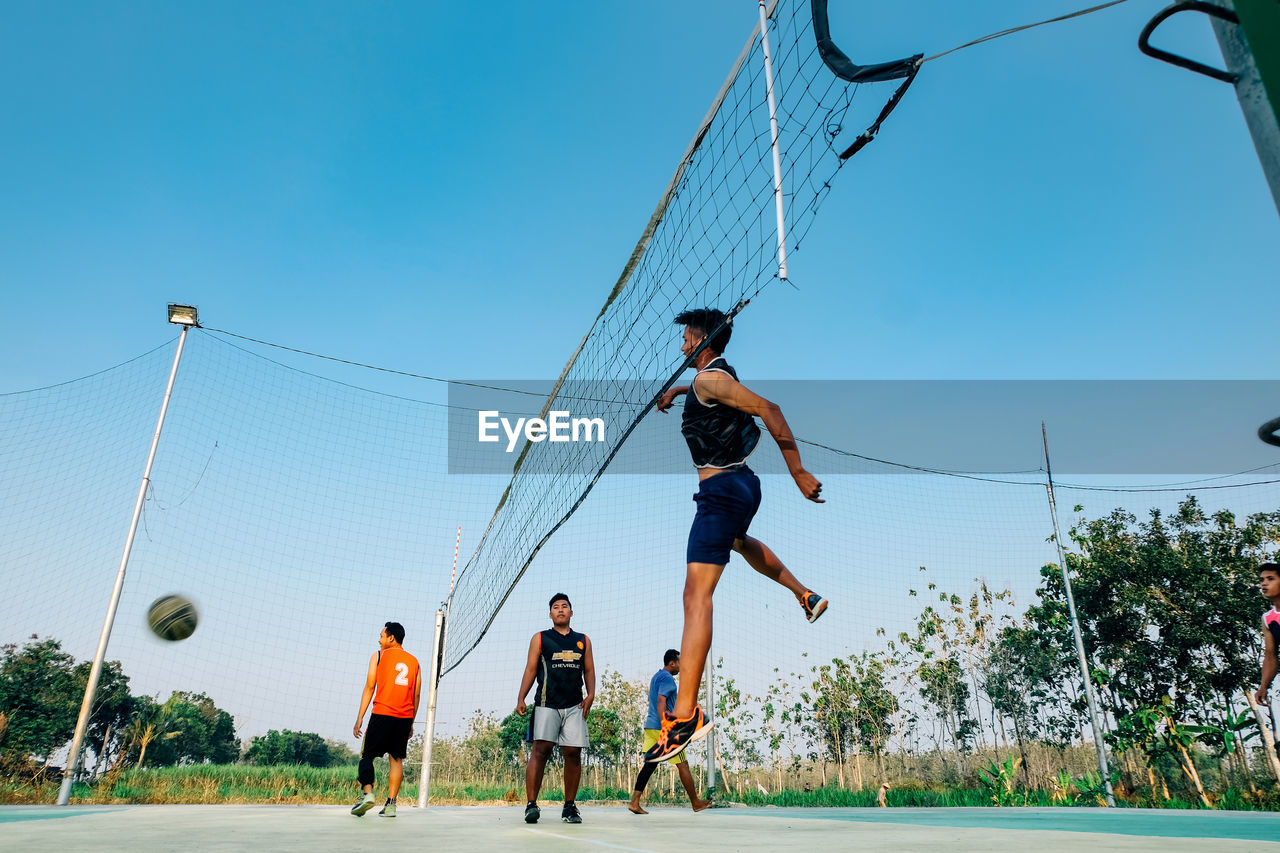 PEOPLE PLAYING SOCCER AGAINST SKY