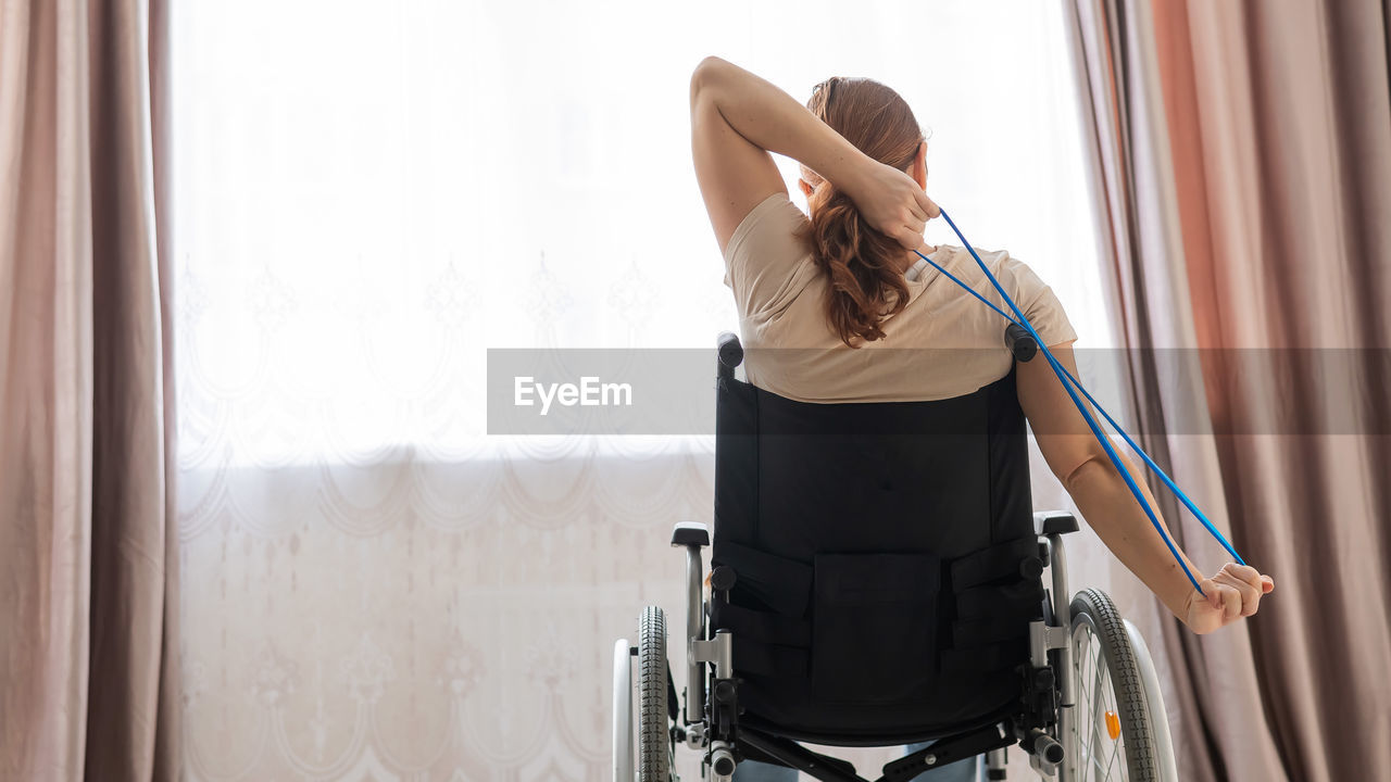 Rear view of woman sitting on wheelchair