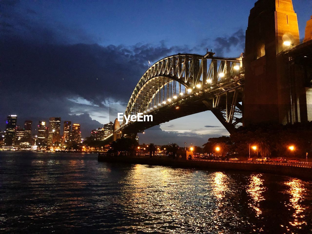 Illuminated bridge over river in city at night