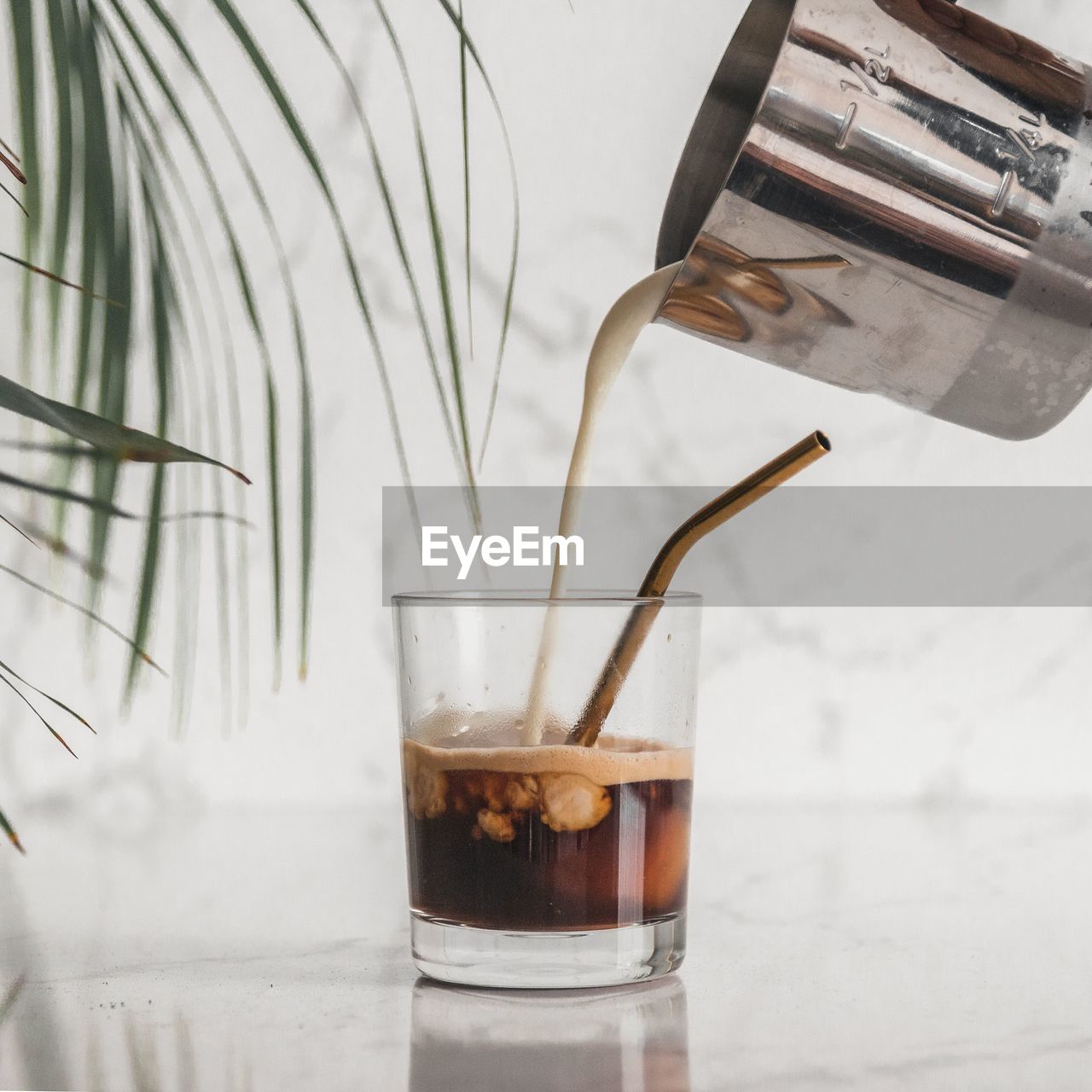 Close-up of milk being poured into coffee on white marble table