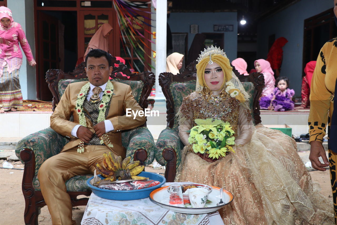 Portrait of bridegroom sitting on chair during wedding ceremony