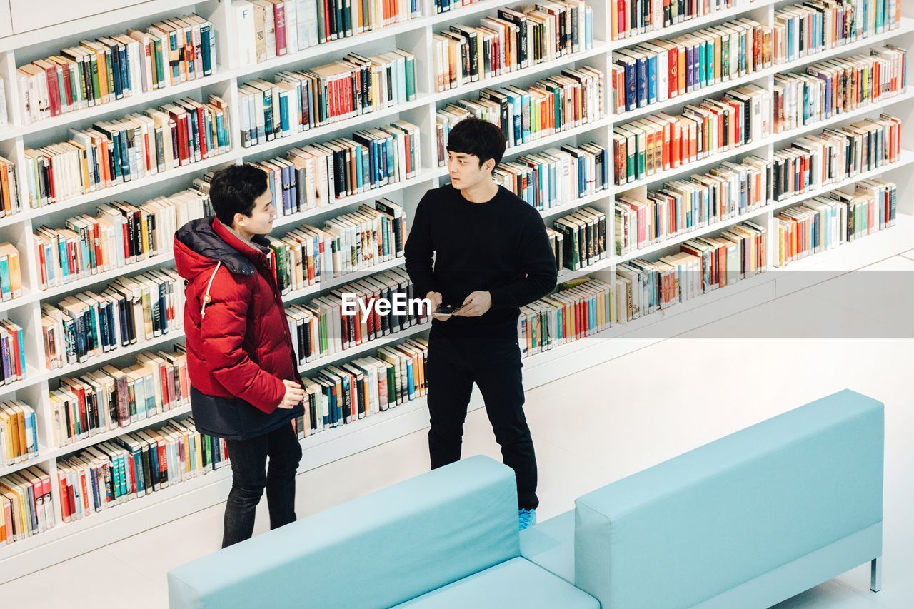 FULL LENGTH OF WOMAN STANDING BY BOOKS