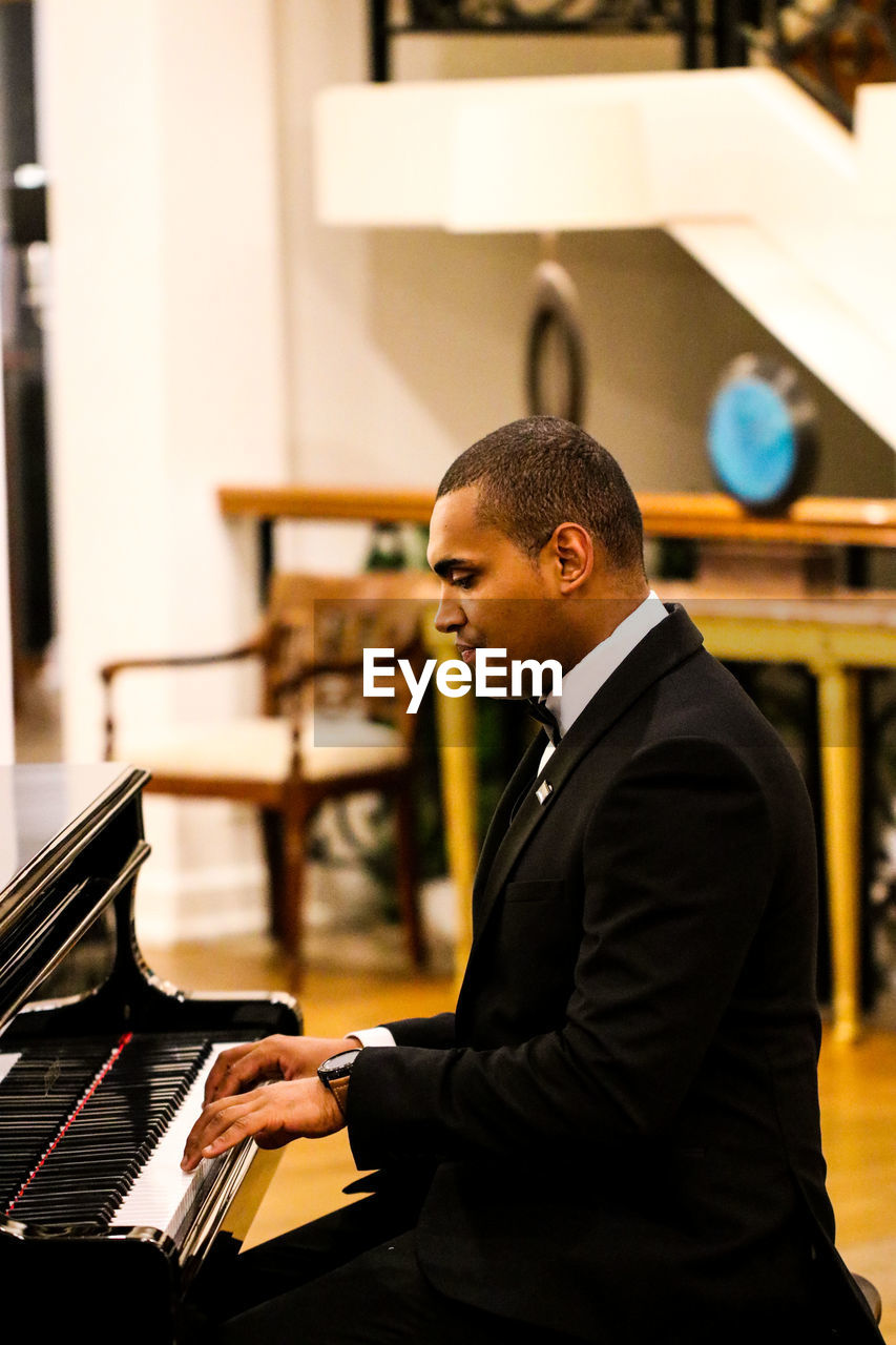 Side view of man playing piano indoors