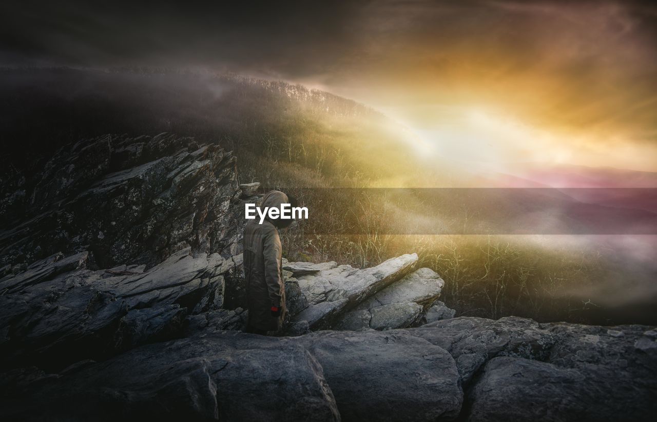 Female hiker standing on mountain against sky during sunset