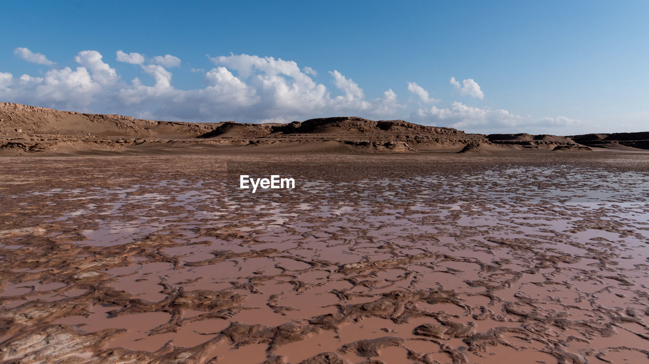 Gathered water in a arid lake in dasht e lut or sahara desert with cloudy sky