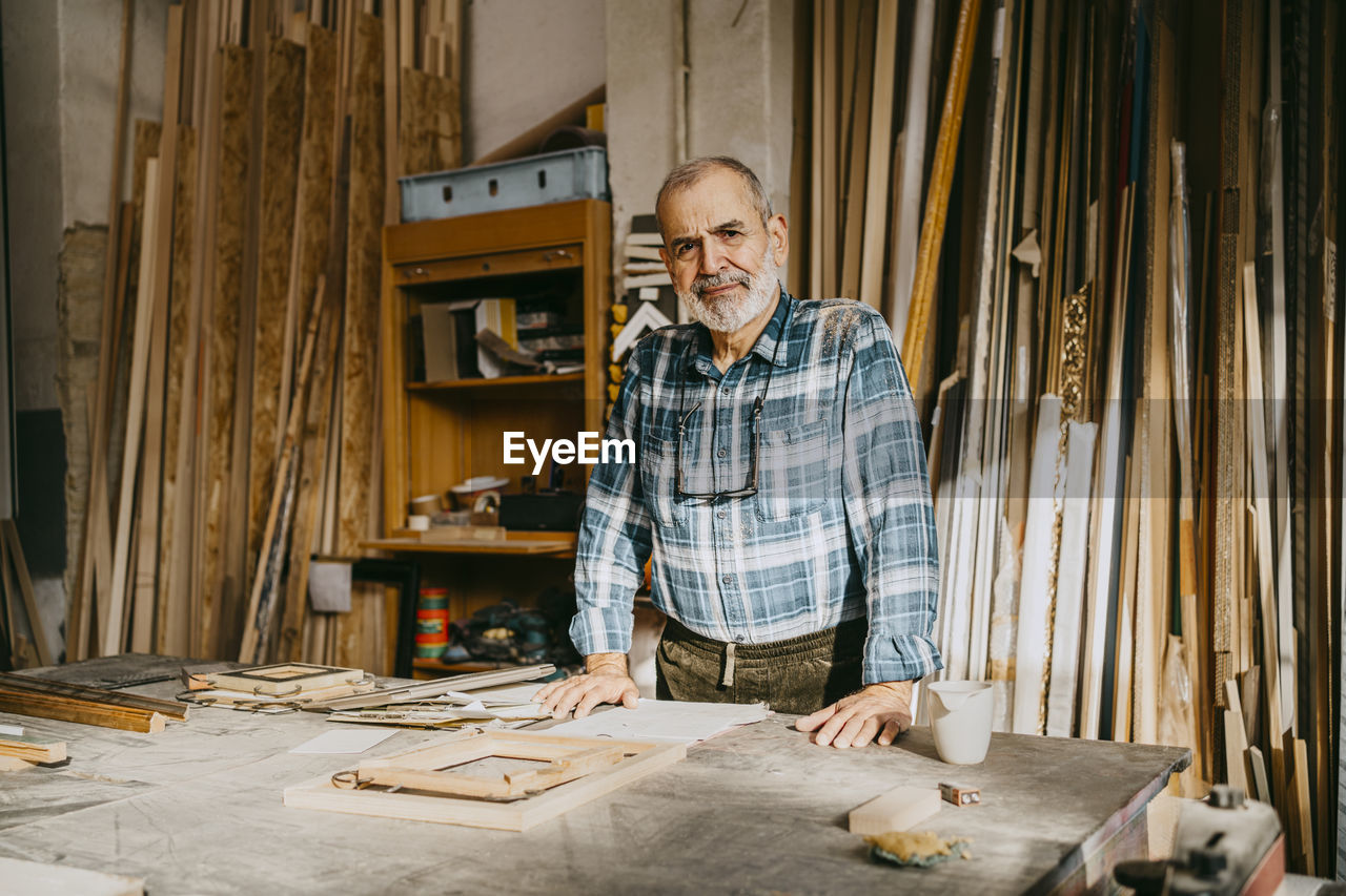 Portrait of confident male carpenter standing in repair shop