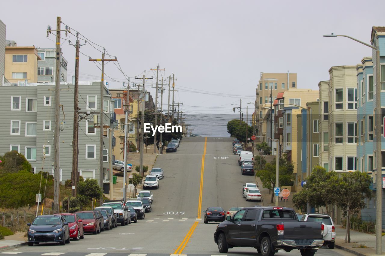 CARS ON ROAD AGAINST CLEAR SKY IN CITY